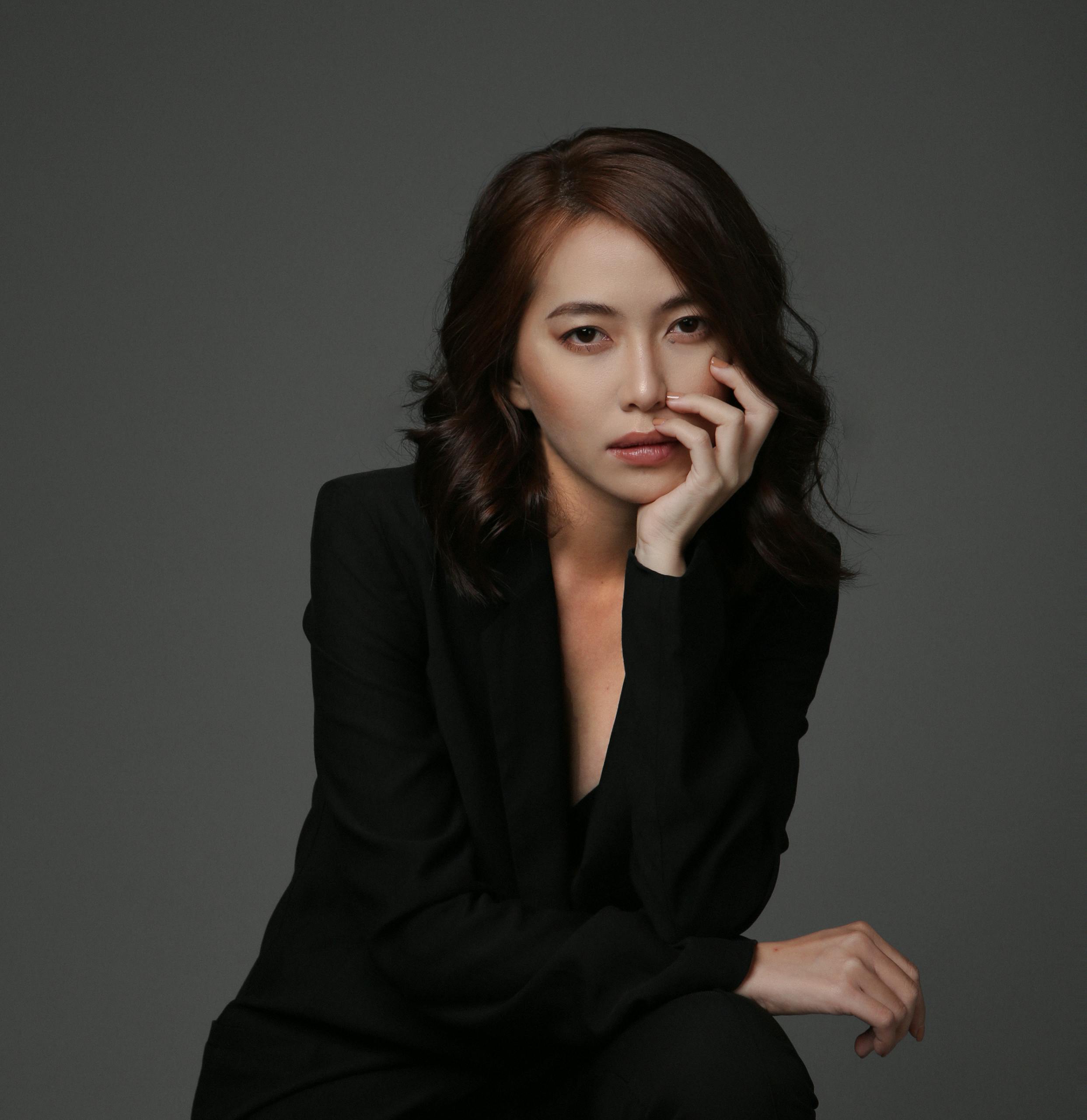 Elegant portrait of an Asian woman in a classic black suit, exuding confidence and grace.